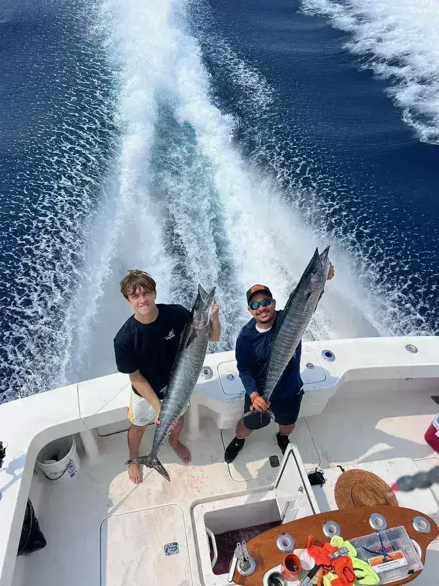 Dos tripulantes sostienen un wahoo en la cubierta del Vuelto Loco